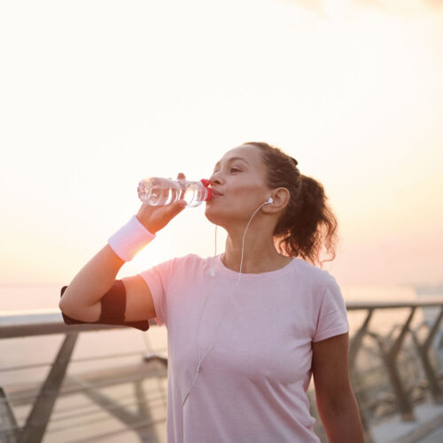 Young latina woman drinking water and excercising by the beach | Aesthetics Beauty Boutique | Miami Florida